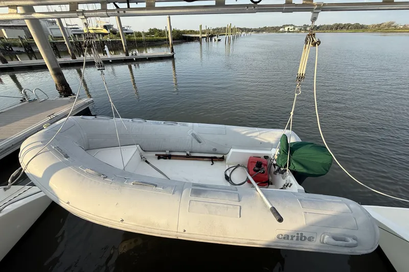 Slide: The Image of Inflatable dinghy suspended over water, near dock, with visible equipment and serene background. - 33
