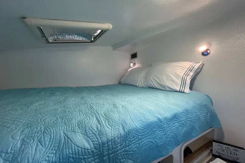 Slide: The Image of Cozy cabin bed in a 2002 Voyage 440, featuring blue quilt and reading lights. - 30