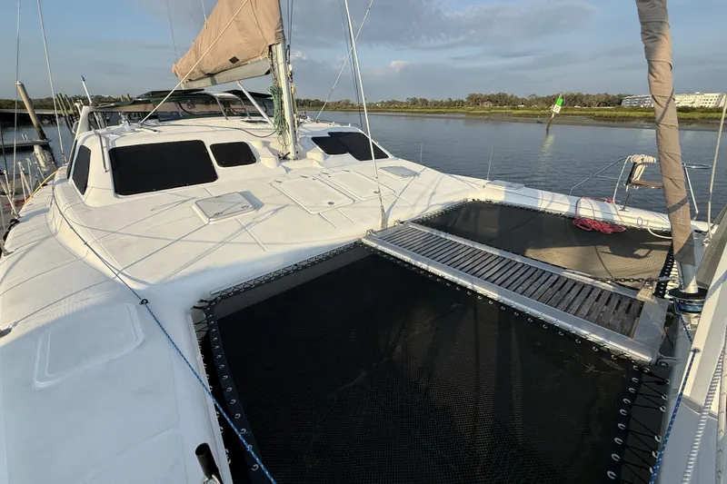 Slide: The Image of 2002 Voyage 440 catamaran on calm water, featuring spacious deck and netting. - 3