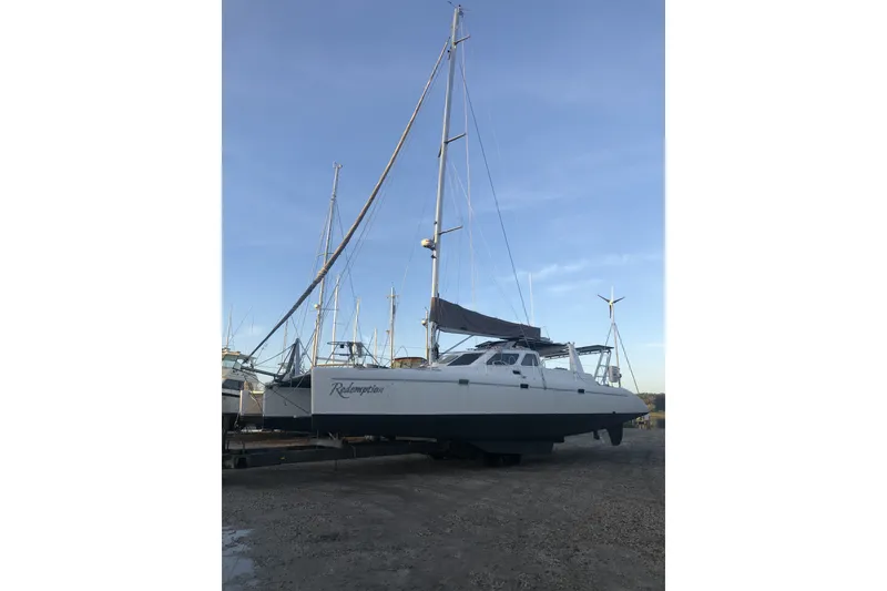 Slide: The Image of 2002 Voyage 440 catamaran on land, named "Redemption," under clear blue sky. - 37