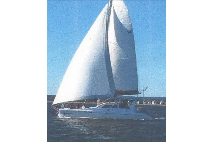 Slide: The Image of Sailing catamaran Voyage 440, 2002 model, gliding on open water under clear blue skies. - 34
