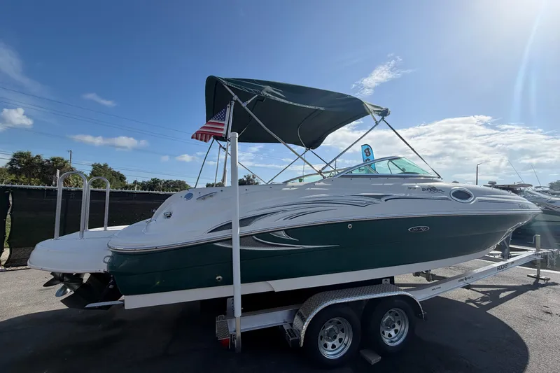 Slide: The Image of 2005 Sea Ray 240 Sundeck boat on trailer, featuring a green hull and canopy. - 2