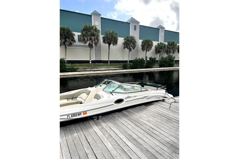 Slide: The Image of 2005 Sea Ray 240 Sundeck boat docked by a canal with palm trees. - 2