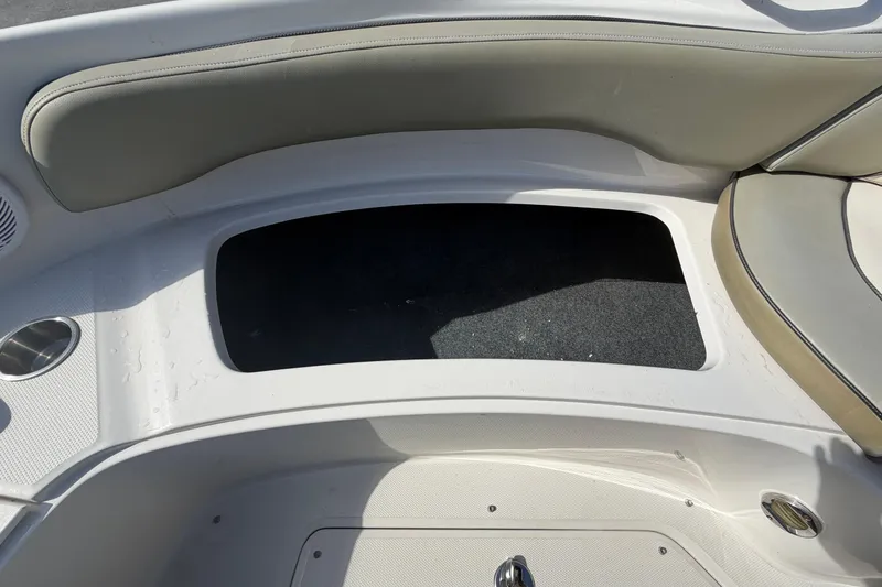 Slide: The Image of 2005 Sea Ray 240 Sundeck boat interior storage compartment with cushioned seating and cup holder. - 49