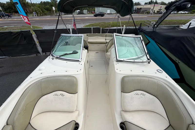 Slide: The Image of 2005 Sea Ray 240 Sundeck boat with open seating and windshield, parked outdoors. - 20