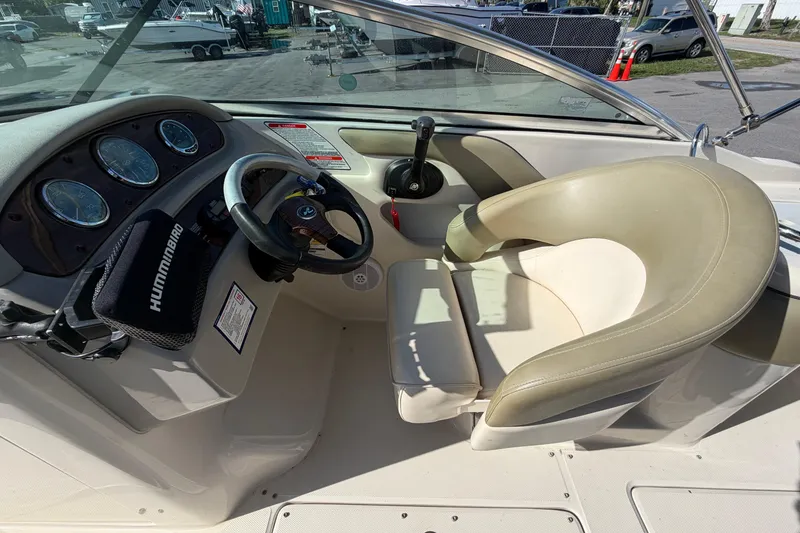 Slide: The Image of 2005 Sea Ray 240 Sundeck cockpit with steering wheel and beige seating. - 23