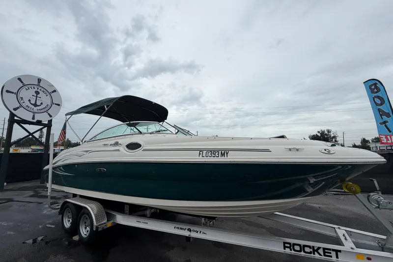The Image of 2005 Sea Ray 240 Sundeck boat on trailer, displayed outdoors under cloudy sky. - 0