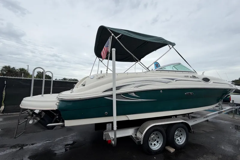 Slide: The Image of 2005 Sea Ray 240 Sundeck boat on trailer, featuring green and white design with canopy. - 2