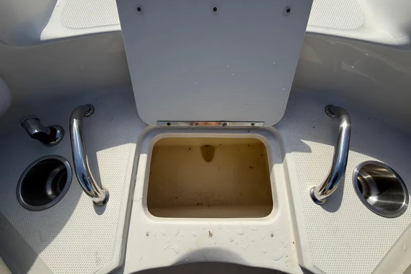Slide: The Image of An open storage compartment on a 2005 Sea Ray 240 Sundeck with stainless steel handles and cup holders. - 52
