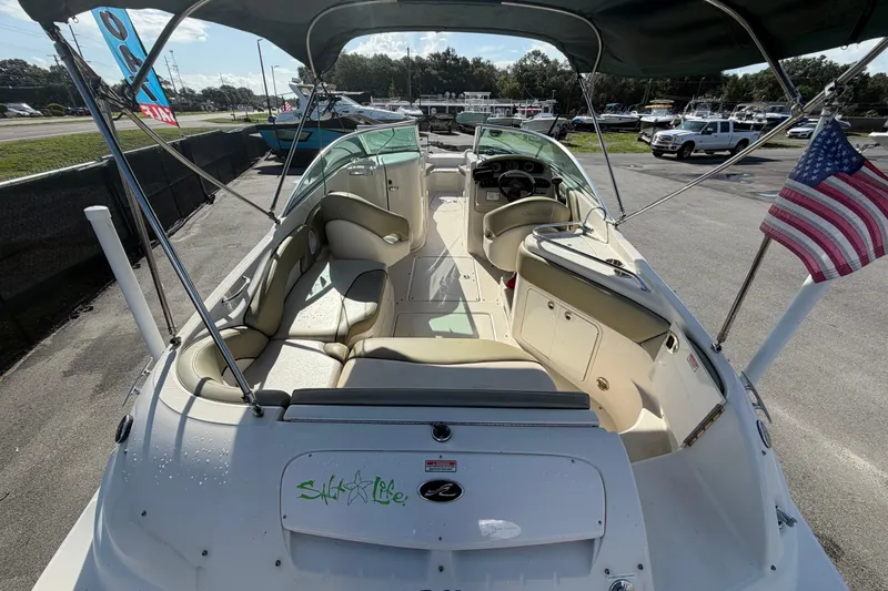 Slide: The Image of 2005 Sea Ray 240 Sundeck boat with spacious seating and American flag, docked outdoors. - 12
