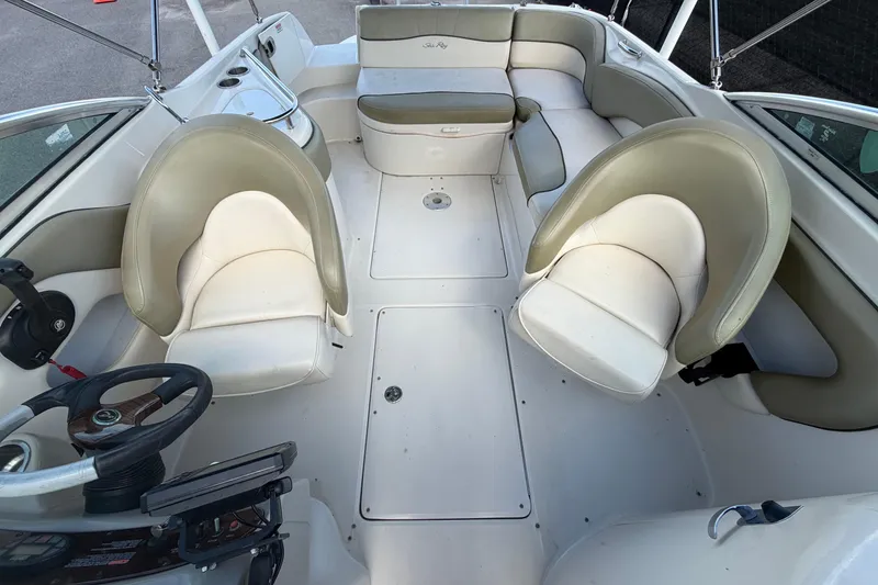 Slide: The Image of 2005 Sea Ray 240 Sundeck interior with beige seating and steering wheel. - 58