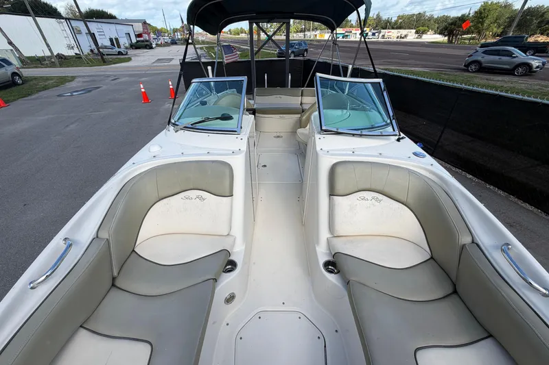 Slide: The Image of 2005 Sea Ray 240 Sundeck boat interior with seating and windshield, parked on pavement. - 57