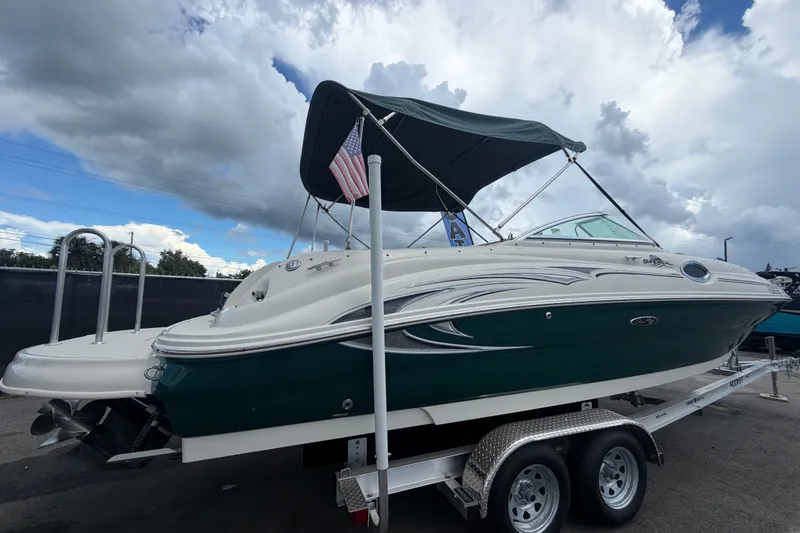 Slide: The Image of 2005 Sea Ray 240 Sundeck boat on trailer with canopy and American flag. - 2