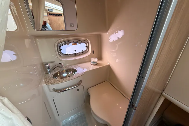 Slide: The Image of 2011 Chaparral 310 Signature boat bathroom with sink, mirror, and porthole window. - 27