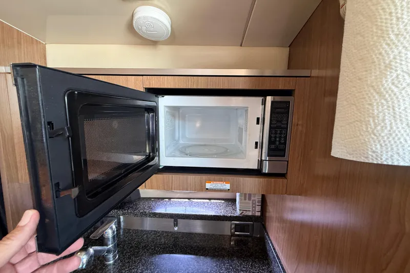 Slide: The Image of Microwave in 2011 Chaparral 310 Signature yacht kitchen, open door, wood cabinetry. - 39