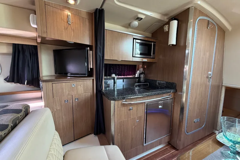 Slide: The Image of 2011 Chaparral 310 Signature yacht interior with kitchenette, TV, and wood cabinetry. - 22