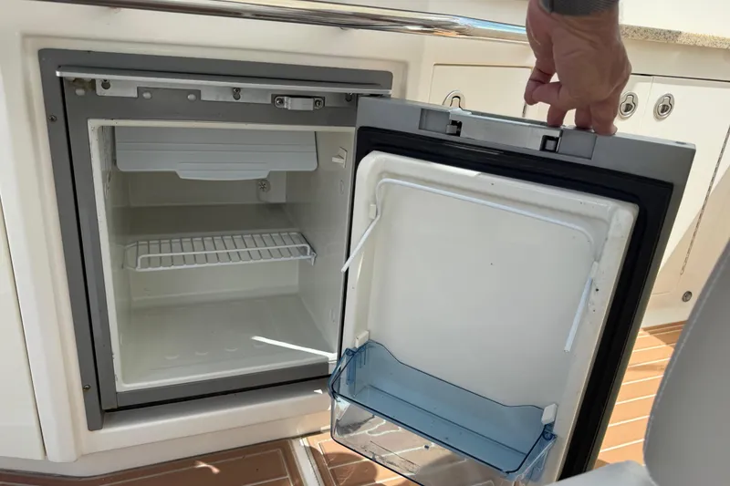 Slide: The Image of Open refrigerator on 2011 Chaparral 310 Signature boat, showing interior shelves and door compartment. - 22
