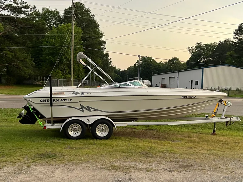 The Image of A white 1995 Checkmate Persuader 234 boat on a trailer beside a road. - 0