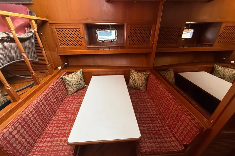 Slide: The Image of Cozy dining area in 1989 Heritage East 40 yacht with red patterned seating and wooden accents. - 28