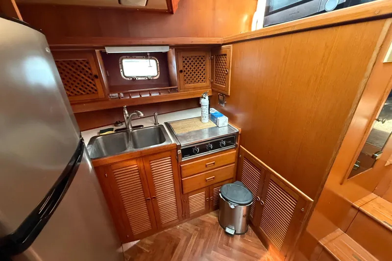 Slide: The Image of Compact kitchen in a 1989 Heritage East 40 boat with wood cabinetry and stainless steel appliances. - 27