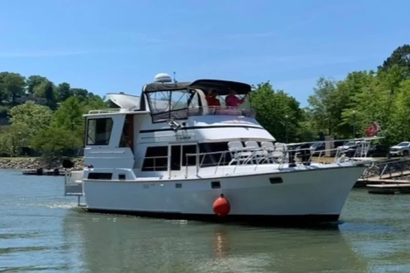 Slide: The Image of 1989 Heritage East 40 yacht cruising on a sunny day with lush greenery in the background. - 2