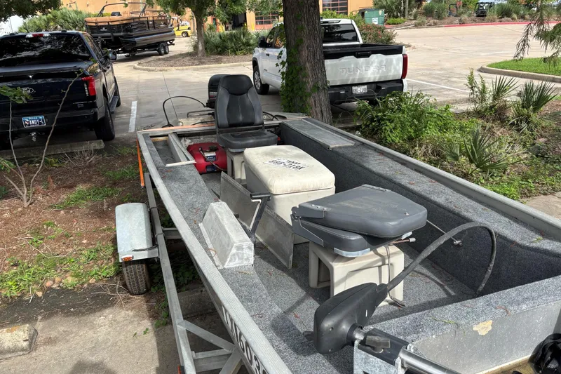 Slide: The Image of 2011 Tracker Panfish 16 boat on trailer in parking lot, surrounded by trucks and greenery. - 5