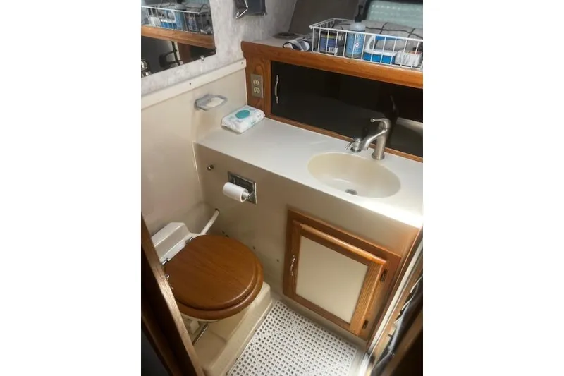 Slide: The Image of 1987 Silverton 34 Convertible boat bathroom with sink, wooden toilet seat, and storage cabinet. - 37