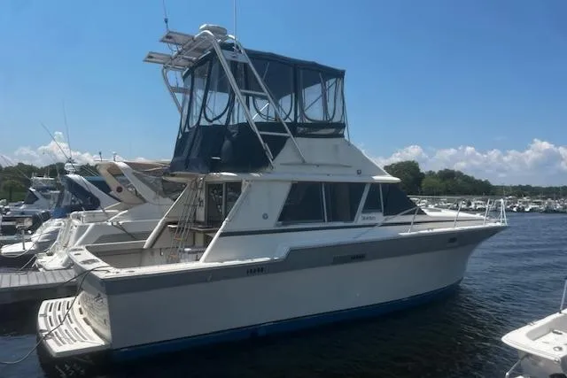 The Image of 1987 Silverton 34 Convertible yacht docked at marina under clear blue sky. - 0