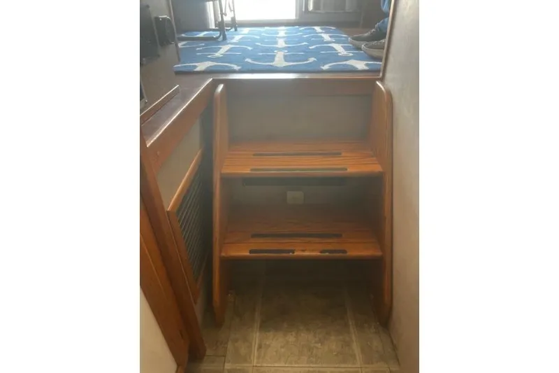 Slide: The Image of Wooden steps inside a 1987 Silverton 34 Convertible boat, leading to a carpeted area. - 21