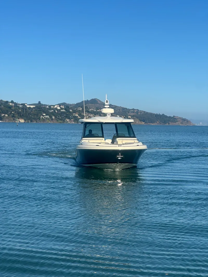 Slide: The Image of A 2023 Chris-Craft Calypso 35 cruising on calm water with hills in the background. - 14