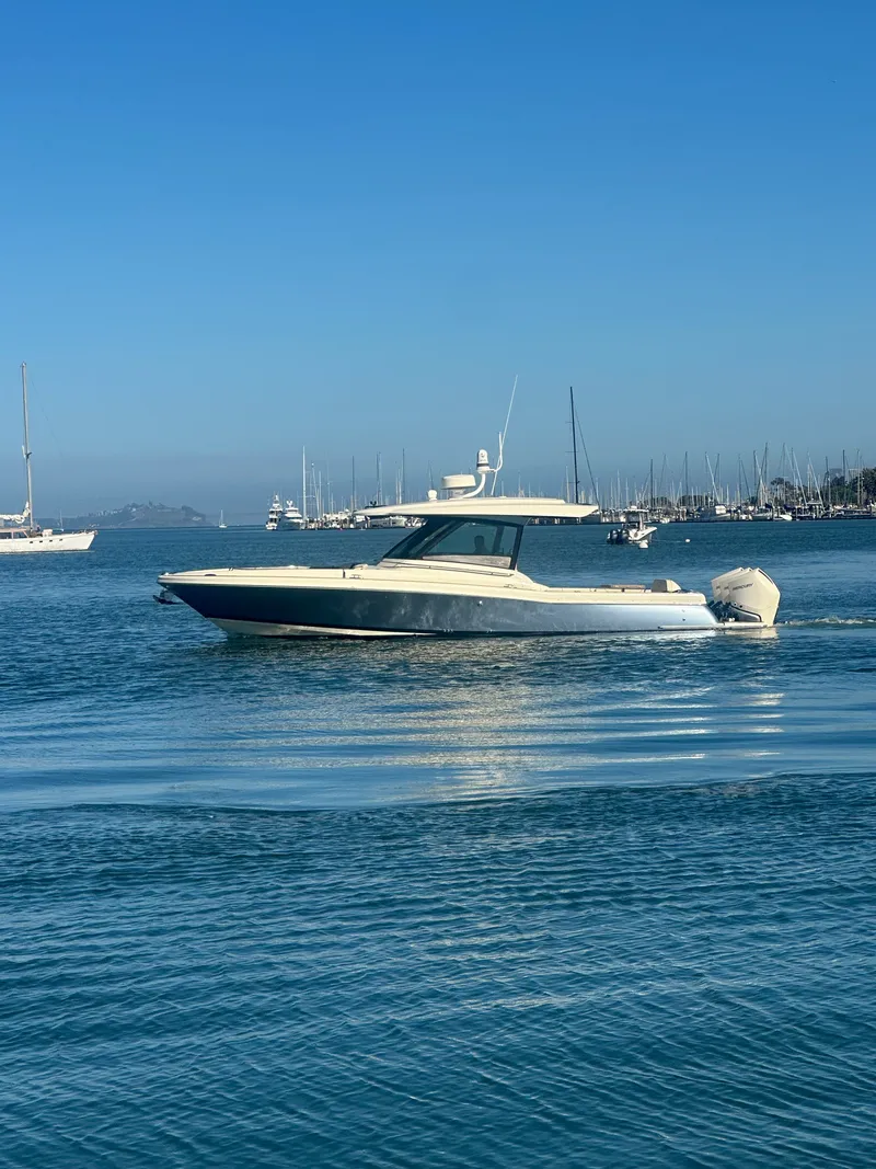 Slide: The Image of A 2023 Chris-Craft Calypso 35 cruising on calm water with a marina in the background. - 6