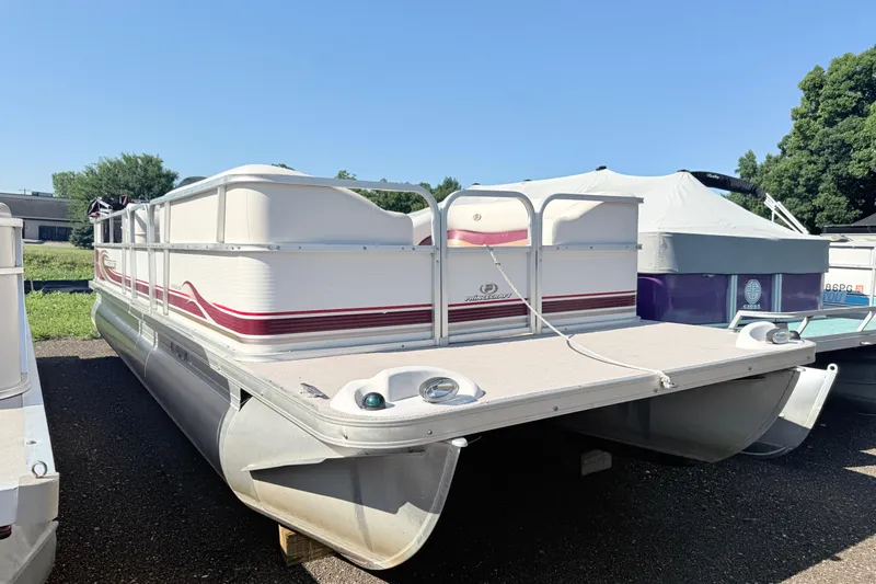 The Image of 2002 Princecraft Vantage 24 L pontoon boat with white and red accents, parked outdoors. - 1