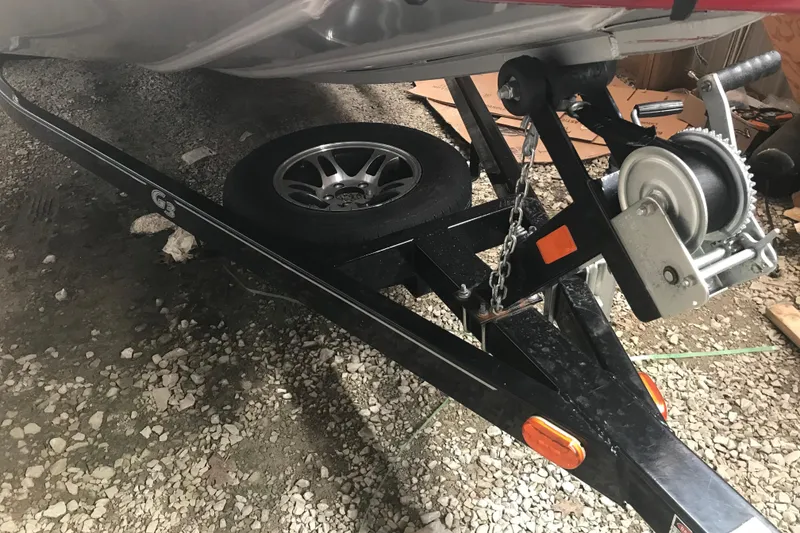 Slide: The Image of 2018 G3 Sportsman 19 boat trailer with winch and spare tire on gravel. - 11