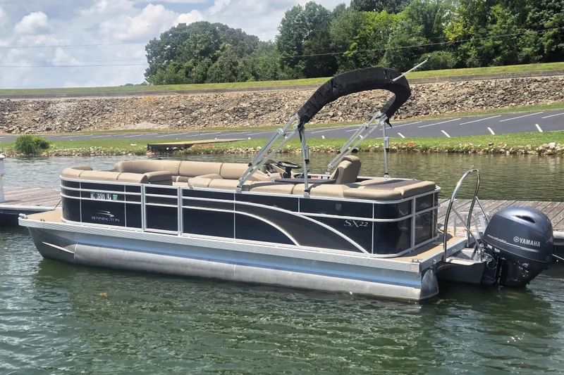 Slide: The Image of A 2019 Bennington SX 22 SLX pontoon boat docked. It features a Yamaha outboard motor. - 2