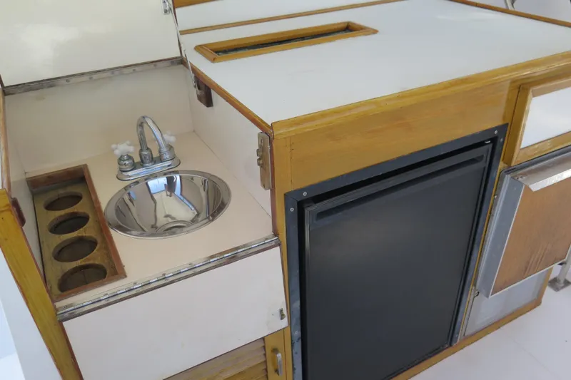 Slide: The Image of 1987 Hershine Aftcabin Motoryacht kitchen with sink, fridge, and wooden cabinetry. - 11