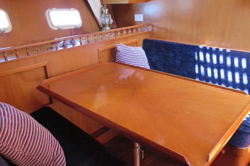 Slide: The Image of Cozy dining area in 1987 Hershine Aftcabin Motoryacht with wooden table and striped cushions. - 27