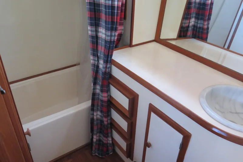 Slide: The Image of 1987 Hershine Aftcabin Motoryacht bathroom with plaid shower curtain and wooden cabinetry. - 37