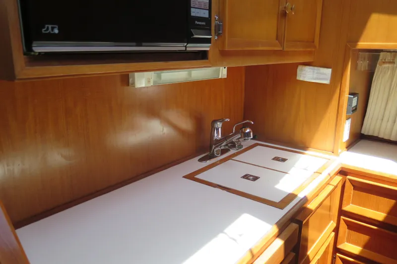 Slide: The Image of 1987 Hershine Aftcabin Motoryacht kitchen with wooden cabinets and countertop sink. - 24