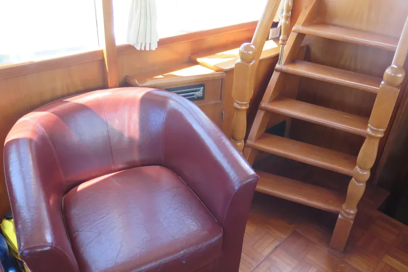 Slide: The Image of 1987 Hershine Aftcabin Motoryacht interior with red leather chair and wooden staircase. - 23