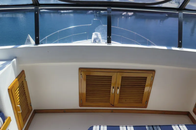 Slide: The Image of 1987 Hershine Aftcabin Motoryacht cockpit with wooden cabinets and water view. - 10
