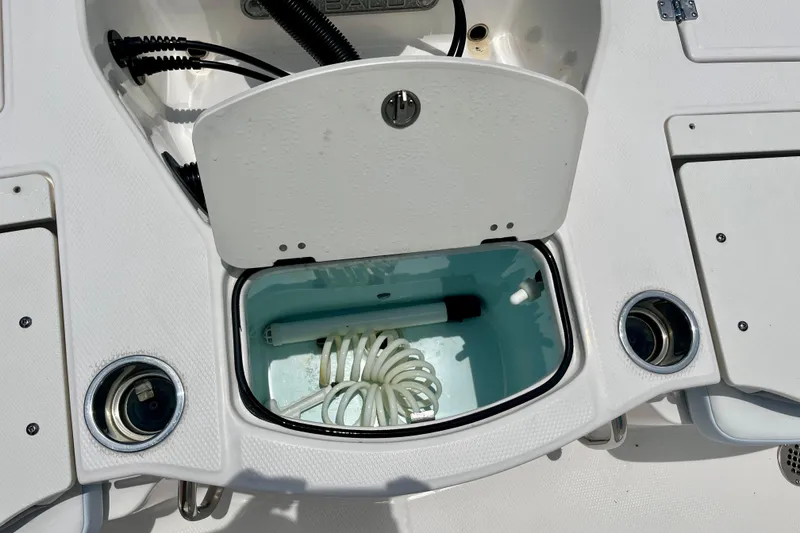 Slide: The Image of 2024 Robalo 206 Cayman boat storage compartment with coiled hose and cup holders. - 12