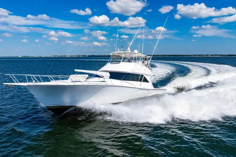 The Image of 2006 Viking 56 Convertible yacht cruising on open water under a clear blue sky. - 0