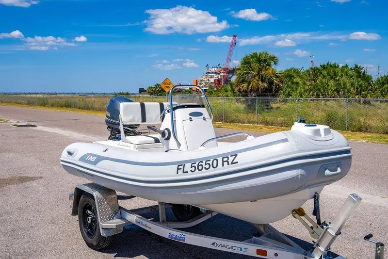 Slide: The Image of A small inflatable boat on a trailer, parked near a fence with palm trees. - 57