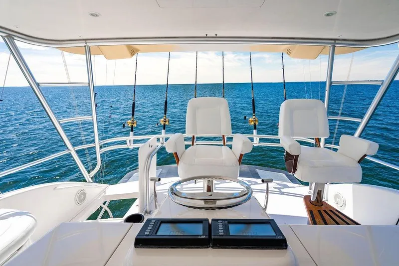 Slide: The Image of Luxury Viking 56 Convertible yacht cockpit with ocean view, featuring fishing rods and captain's chairs. - 35