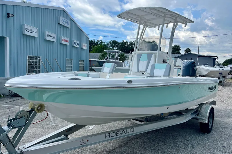 Slide: The Image of 2024 Robalo 206 Cayman boat on trailer, displayed outside dealership under cloudy sky. - 4