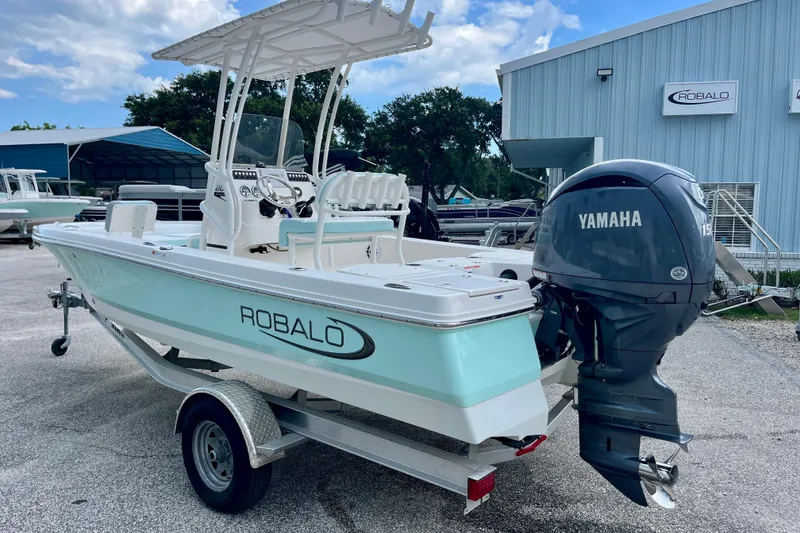 Slide: The Image of 2024 Robalo 206 Cayman boat with Yamaha engine, parked outdoors near a blue building. - 6