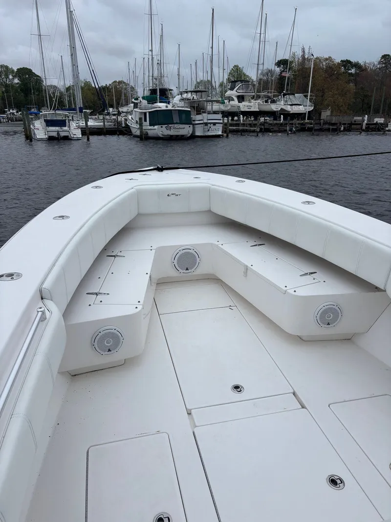 Slide: The Image of Contender 35 ST 2015: Spacious white deck with seating, docked in a harbor with other boats in the background. - 4