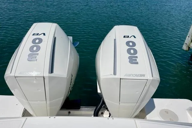 Slide: The Image of Twin Mercury 300 V8 engines on a 2025 Boston Whaler 330 Outrage, docked on calm water. - 18