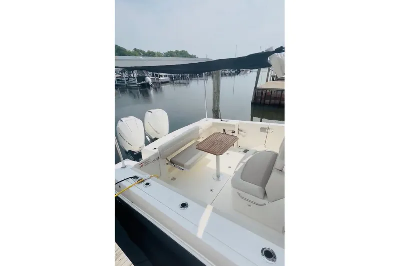 Slide: The Image of 2025 Boston Whaler 330 Outrage boat interior with seating and table, docked at marina. - 19