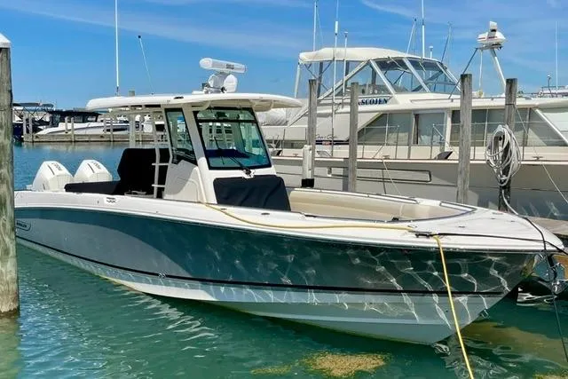 The Image of 2025 Boston Whaler 330 Outrage boat docked in a marina under clear blue skies. - 0